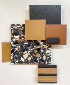 several different colors and shapes of tile on a white wall, including black, brown, yellow, and orange