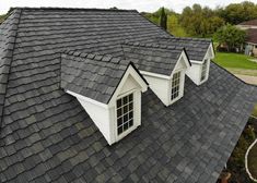 a roof with three windows and two dormers on the top, in front of a house