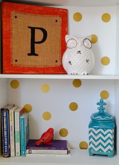 two bookshelves with polka dot wallpaper and an owl figurine on top