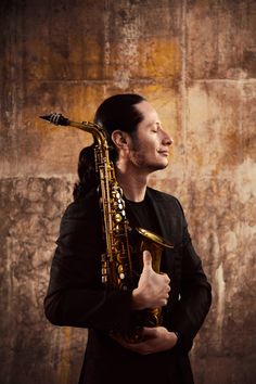 a man with long hair holding a saxophone