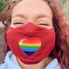 a woman wearing a red face mask with a rainbow heart on the front and side