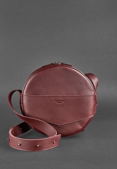 Introducing our premium handcrafted round crossbody bag designed for the modern woman. This sophisticated bag blends style and functionality, making it the perfect accessory for both daily and evening use. Key Features: Spacious Interior: Generously accommodates your essentials, including a small tablet or document folder. Organized Storage: Features one large compartment, a dedicated pocket with a strap and button closure, and two patch pockets. Secure Closure: Equipped with a sturdy zipper for Leather Bags With Round Handle For Gifts, Elegant Shoulder Bag With Detachable Strap And Round Case, Elegant Leather Round Case Bag, Modern Formal Bags With Round Case, Chic Round Case Shoulder Bag For Evening, Chic Round Case Bag For Gift, Modern Round Case Travel Bag, Modern Bags With Removable Pouch And Round Case, Chic Leather Round Case Shoulder Bag