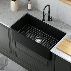 a black kitchen sink sitting on top of a counter next to a wooden cutting board