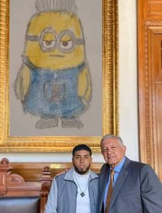 two men standing next to each other in front of a painting