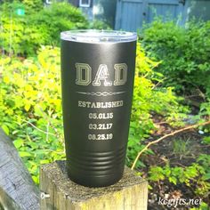 a black tumbler sitting on top of a wooden post