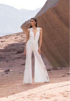 a woman in a white dress is standing on the desert with her hands behind her back