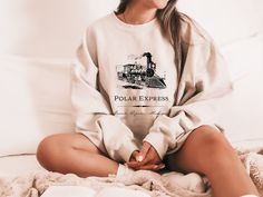 A uniquely designed Polar Express sweatshirt. All rights for characters and book references to Chris Van Allsburg.  -The collar is ribbed knit, so it retains its shape even after washing. There are no itchy side seams on these sweaters! -50% cotton, 50% polyester -Loose fit -Runs true to size Chris Van Allsburg, Michigan Sweatshirt, The Polar Express, Polar Express, Sweater Christmas, Bookish Gifts, Sweatshirt Christmas, Gifts For Readers, Unique Christmas