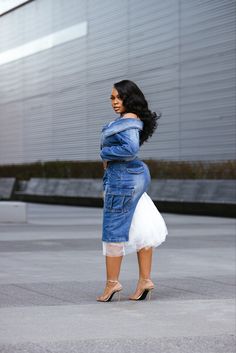 a woman in a blue jean jacket and white dress