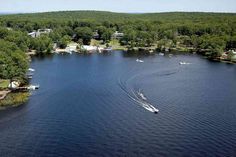 an aerial view of a lake with boats in the water and lots of trees around it