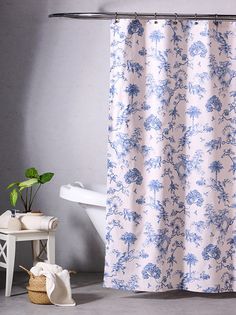 a blue and white shower curtain next to a bath tub with a plant in it