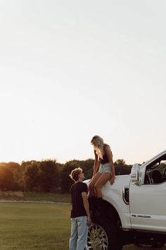 a man standing next to a woman on the back of a white pick up truck