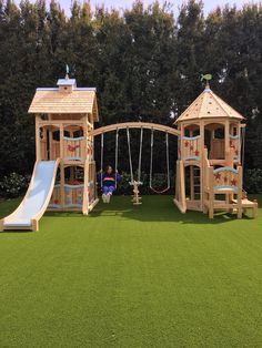 a children's play area with swings, slide and climbing frame in the grass