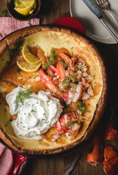 a lobster pot pie with sour cream and lemon wedges