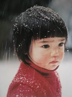 a young child wearing a red sweater standing in the snow