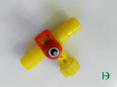 a yellow plastic object with a red handle on the end and a black eyeball in the middle