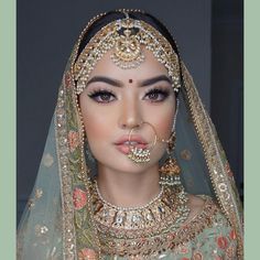 a woman in a bridal outfit with jewelry on her nose and nose ring, wearing an elaborate head piece