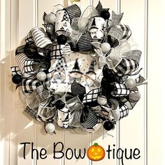 a black and white halloween wreath hanging on a door with the words, the bowtiquee