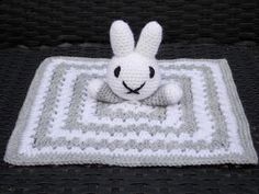 a white crocheted bunny sitting on top of a blanket