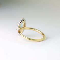 Our Posy setting is for a one-of-a-kind lady. It is two tone ring, made up of white and yellow gold. A marquise shaped sapphire has been hand-selected for its unique color and shape. Bubbly champagne diamonds are bead-set in the matte white gold halo. About this ring: 14k yellow gold shank with a white gold head 1.42ct Marquise shaped sapphire Color: light greenish grey blue Other stones: ten 0.15ctw champagne diamonds Clarity SI1 Finger size 6, resizable between sizes 5 and 7 This piece is in s Luxury Marquise Emerald Ring With Diamonds, Luxury Marquise Halo Diamond Ring, Modern Marquise Cut Gemstone Rings, Luxury Marquise Gemstone Diamond Ring, Luxury Marquise Emerald Ring With Prong Setting, Fine Jewelry Marquise Cut Halo Ring For Promise, Marquise White Gold Diamond Ring With Halo, Marquise Halo Diamond Ring In White Gold, Fine Jewelry Emerald Ring With Marquise Brilliant Cut