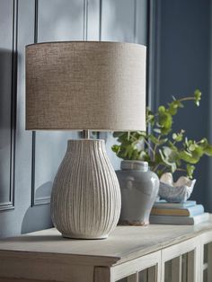 a white vase sitting on top of a table next to a lamp