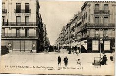 an old black and white photo of people walking down the street in front of buildings