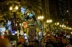 an elaborately dressed man in the middle of a crowd at night with lights on