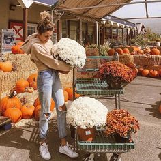 a woman standing in front of pumpkins and hay bales with flowers on them