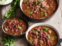 three bowls filled with chili and beans on top of a table