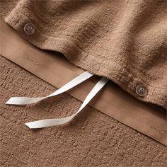 a white ribbon is tied to the side of a brown jacket