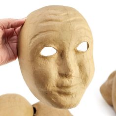 a person holding up a wooden mask to their face