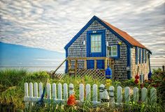 a blue house sitting on top of a lush green field