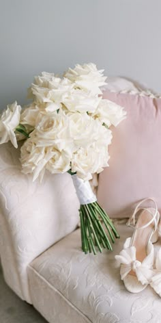 the bridal bouquet and shoes are sitting on the couch next to the pillow,