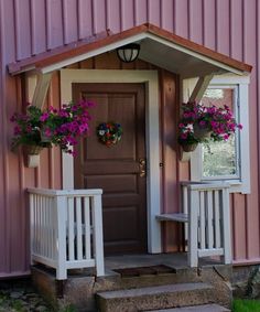 a pink house with flowers on the front porch and steps leading up to the door