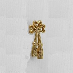 a gold brooch with flowers hanging from it's side on a white wall