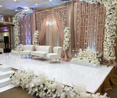 a wedding stage decorated with white flowers and chairs