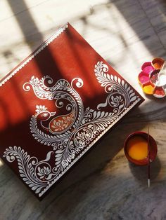 a table topped with a red and white tray covered in paisley designs next to candles