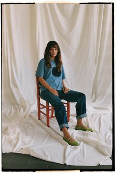 a woman sitting in a chair with her legs crossed and green shoes on the ground