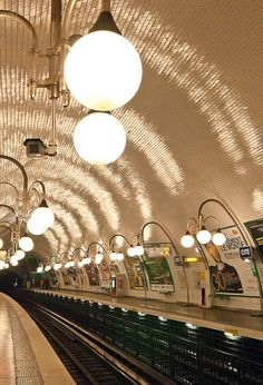 an empty subway station with lights hanging from the ceiling