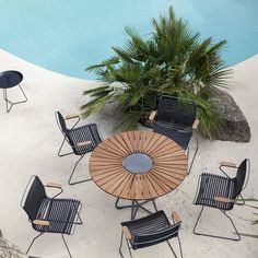 an outdoor table and chairs near a pool