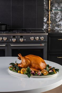 a roasted turkey on a white plate in front of an oven with black cabinets and drawers