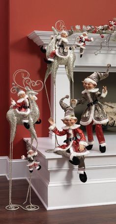 christmas decorations in front of a fireplace with santa clause and reindeer figures hanging from the mantle