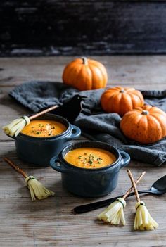 three bowls of pumpkin soup on a wooden table