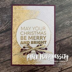 a christmas card with the words merry and bright in gold, on top of a wooden table