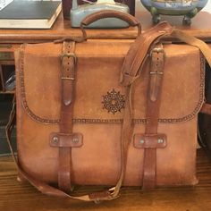 This very vintage leather bag is an artisan piece, with provenance in East Tennessee.  The detail here is excellent, with naturally tanned leather, buckles and satchel style binding straps.  Broad hand lacing details at the side were used to layer double side panels, giving the bag amazing stability.  There are 3 divided sections and a couple of slip pockets on the inside, the dividers are also in the lacing. This comes from the era of craft fairs that were most prevalent in the 60's and 70's. The hippy, and arts and crafts influences are so obvious here.  Imagine finding this at an outdoor booth at the Ramps Festival of Cosby or maybe from a vendor that traveled to the Dogwood Arts Festival in Knoxville.  Then imagine carrying this bag to your next Renaissance Fair or to your office.  It Vintage Leather Satchel Backpack For Everyday, Vintage Leather Shoulder Backpack For Everyday Use, Vintage Travel Bag With Leather Backing, Vintage Travel Satchel With Leather Handles, Vintage Leather Backpack With Leather Lining, Vintage Satchel With Leather Handles For Travel, Vintage Brown Leather Satchel Backpack, Vintage Brown Leather Backpack For Everyday, Vintage Rectangular Leather Backpack