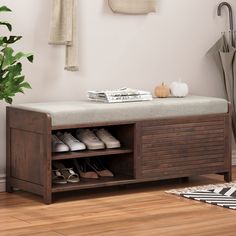 a wooden bench with shoes on it next to a potted plant and coat rack