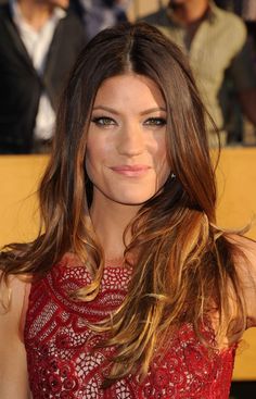 a woman with long brown hair wearing a red dress