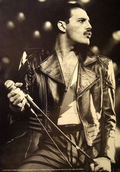 a black and white photo of a man in a leather jacket holding a microphone on stage