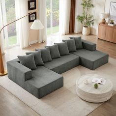 a living room with a large sectional couch and coffee table on the floor in front of windows