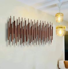 a wall sculpture made out of wood sticks in a living room with two lamps hanging from the ceiling