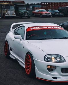 a white car with red rims parked in a parking lot